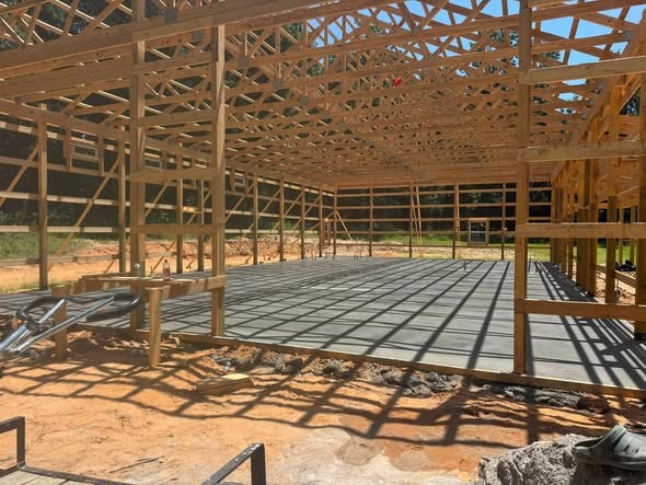 Fresh concrete slab poured inside a pole barn frame