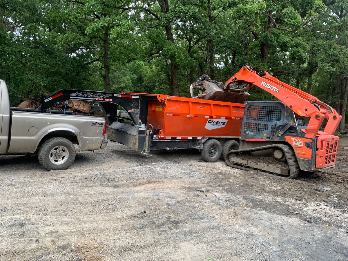 Orange loader filling an On-Site Dumpsters trailer on a job site